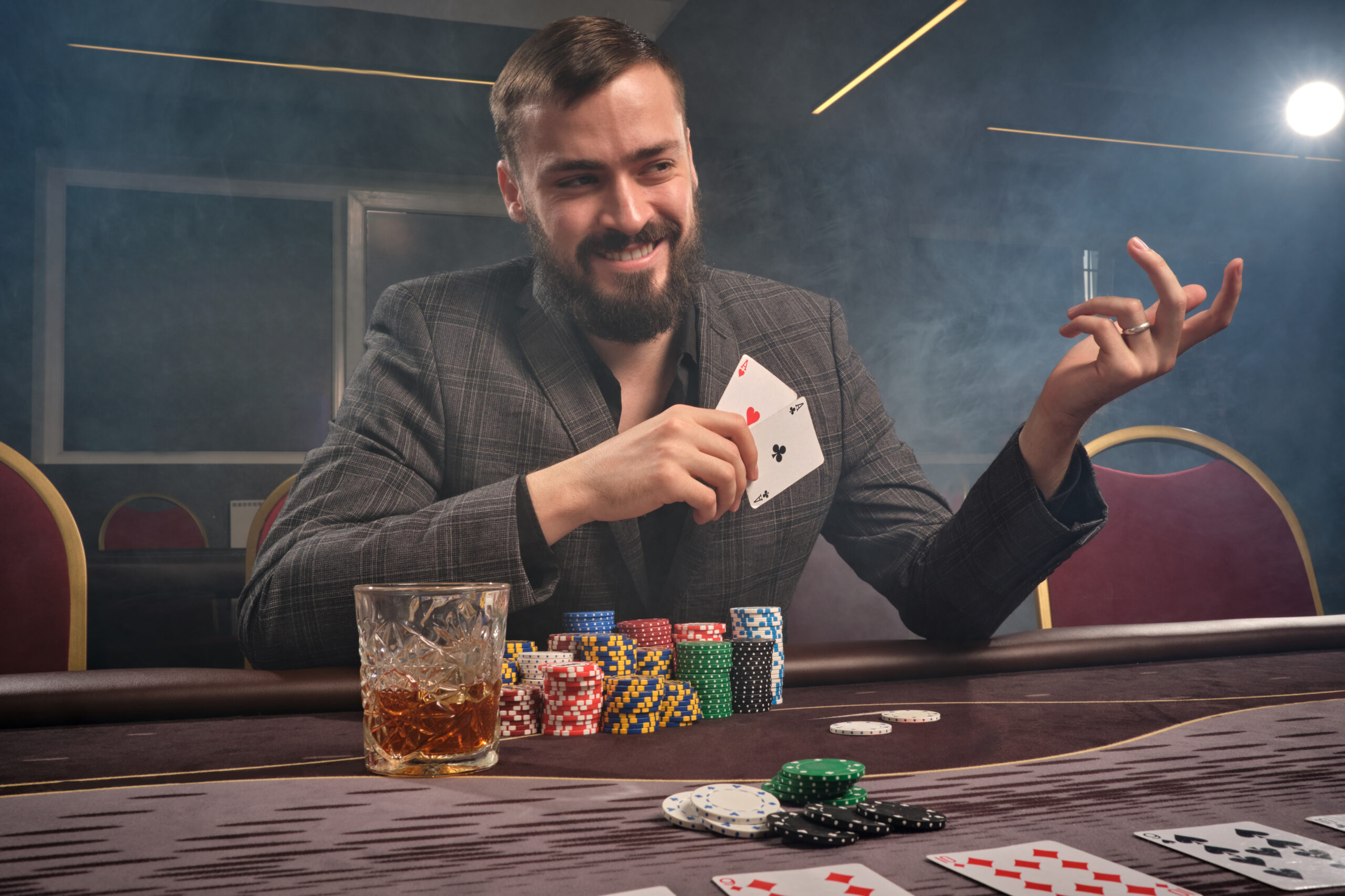 Handsome bearded man is playing poker sitting at the table in casino.